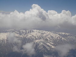 Erg geaccidenteerd terrein met hoge bergtoppen en soliede wolkenformaties, het vliegdecor van Afghanistan.